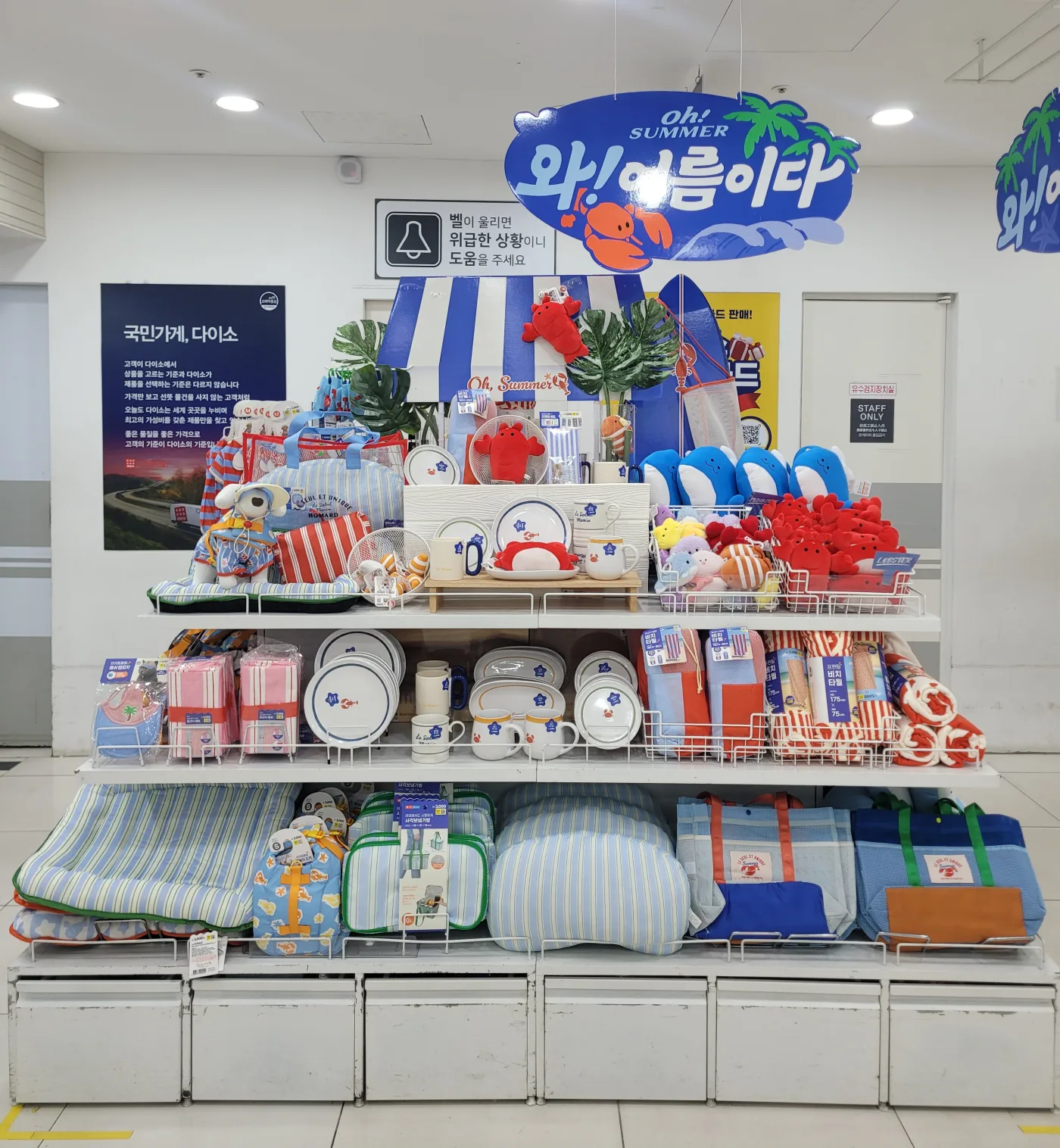 The July 2026 summer display at Daiso Myeongdong Station with striped bags, ceramics, beach blankets, and sea-animal plush toys